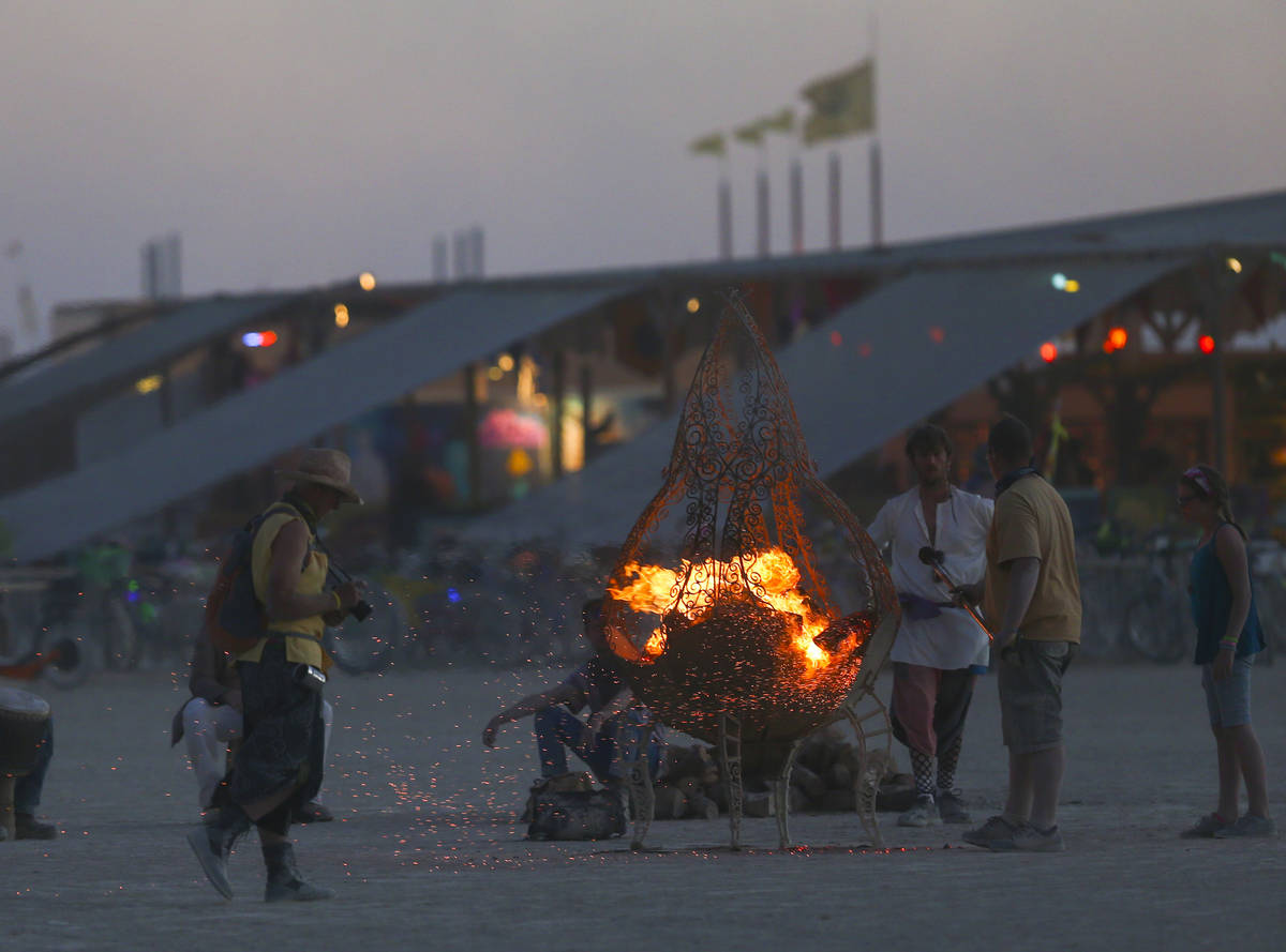 Attendees gather around a fire pit during Burning Man at the Black Rock Desert north of Reno, A ...