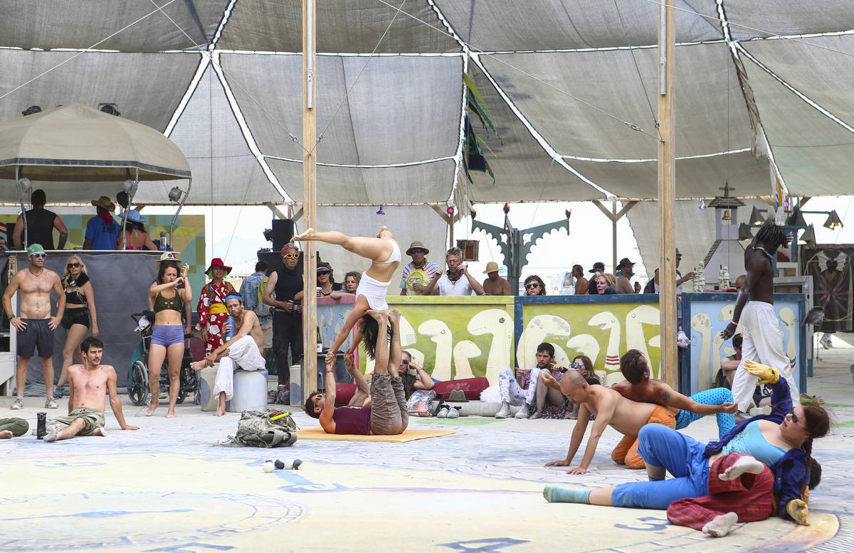Attendees do yoga at the center camp cafe during Burning Man at the Black Rock Desert north of ...