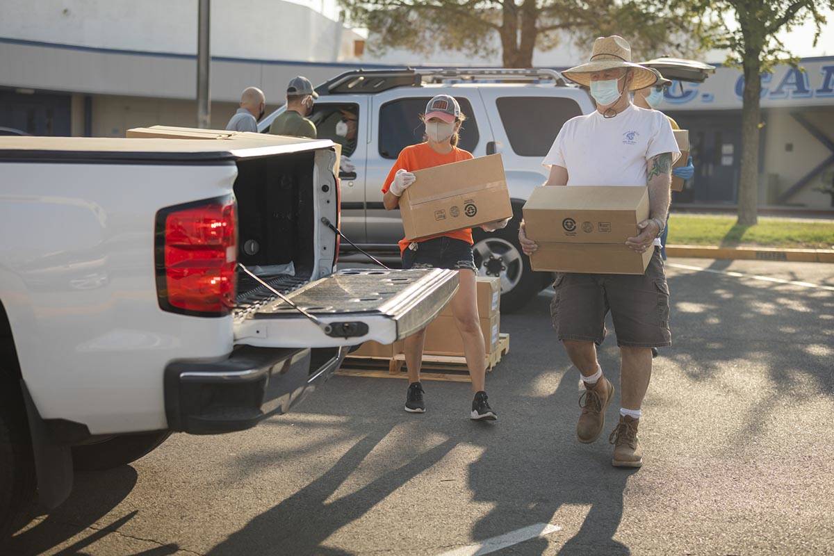 Three Square Food Bank volunteers Dinis Adams, left, and Mark Jantz load a vehicle going throug ...