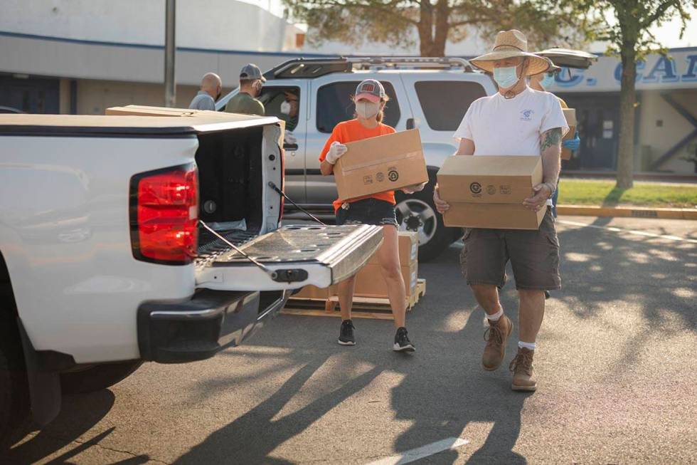 Three Square Food Bank volunteers Dinis Adams, left, and Mark Jantz load a vehicle going throug ...