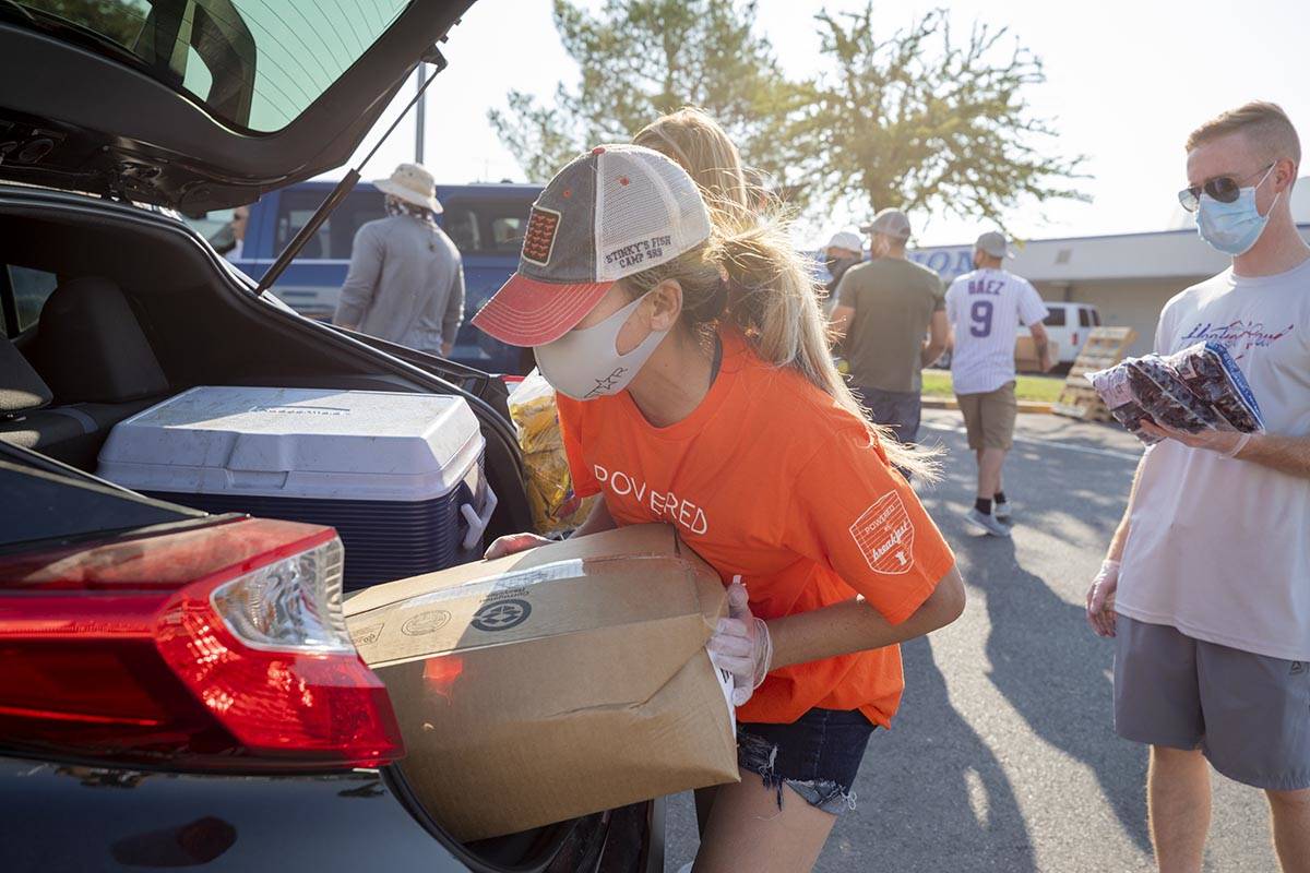 Three Square Food Bank volunteer Dinis Adams of Las Vegas loads a vehicle going through the dri ...