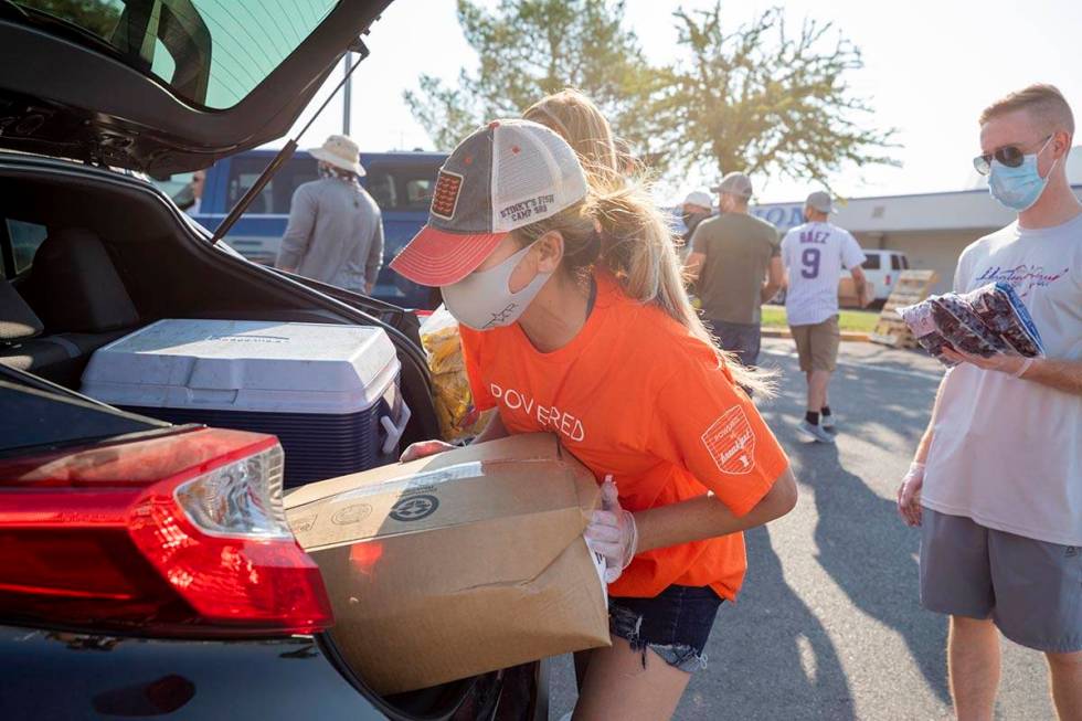 Three Square Food Bank volunteer Dinis Adams of Las Vegas loads a vehicle going through the dri ...