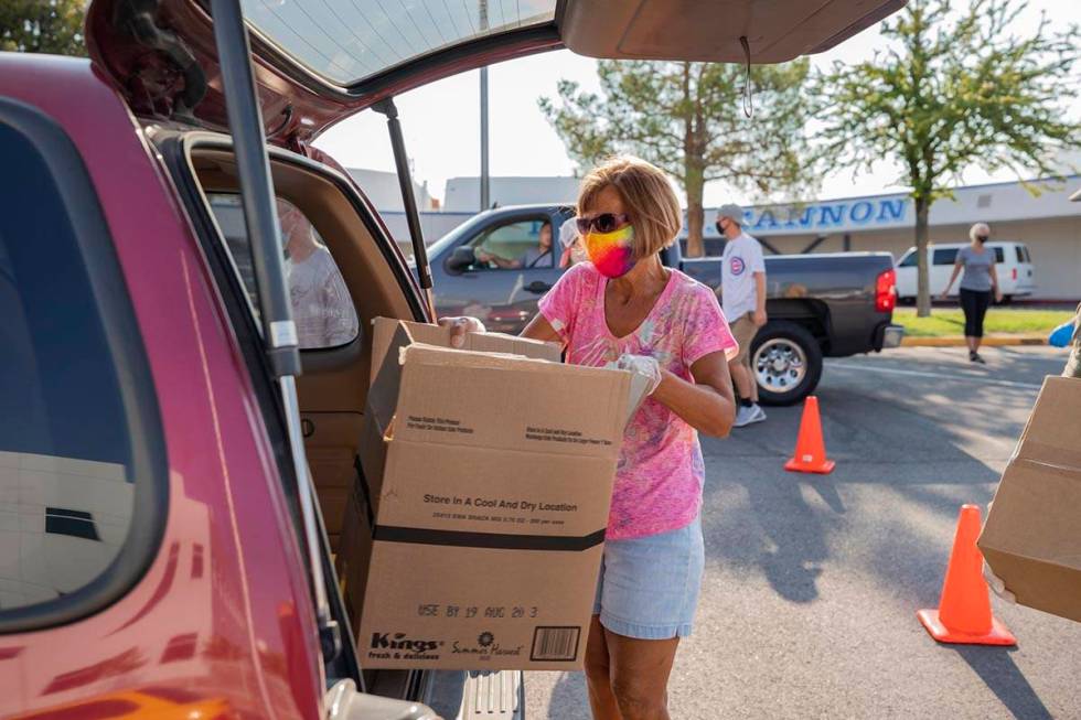 Three Square Food Bank volunteer Julie Sues-Delaney loads a vehicle going through the drive-thr ...