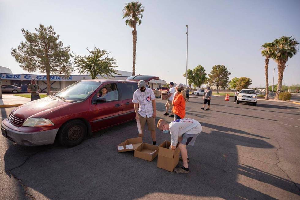 Three Square Food Bank volunteers grab the remaining food items for a vehicle going through the ...