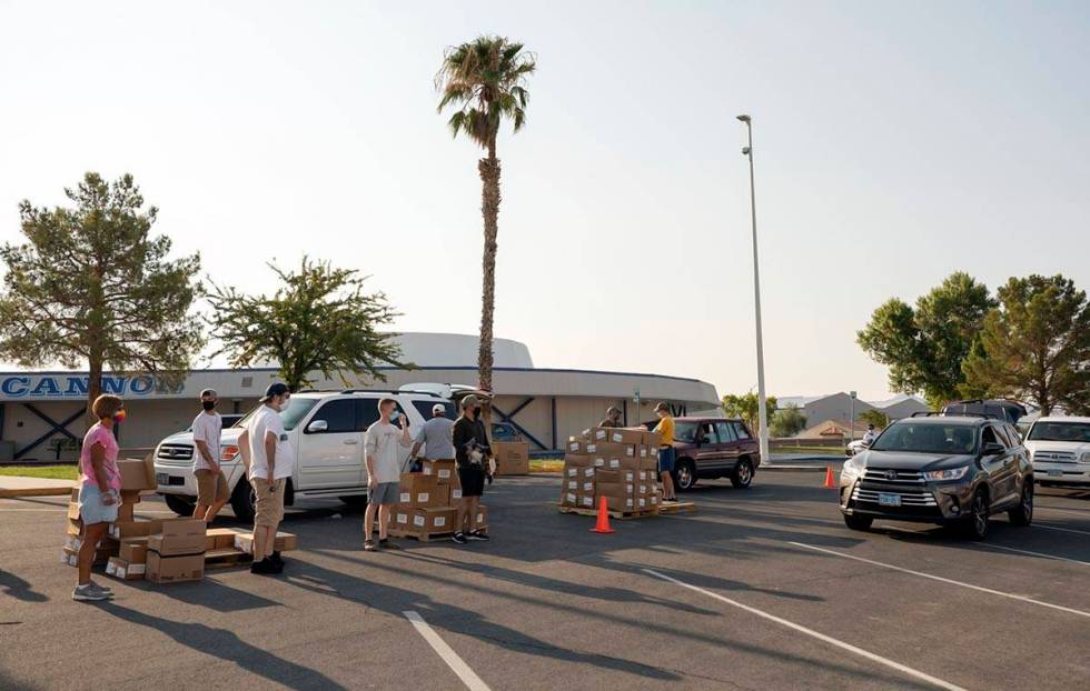 Volunteers with Three Square Food Bank distribute meals at Cannon Junior High School for the co ...