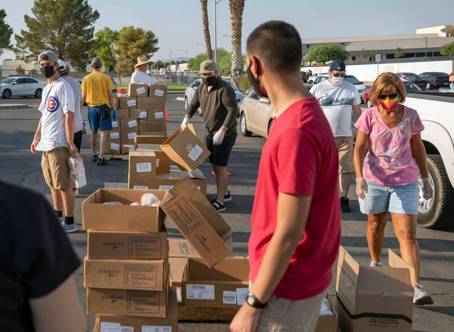 Volunteers with Three Square Food Bank distribute meals at Cannon Junior High School for the co ...