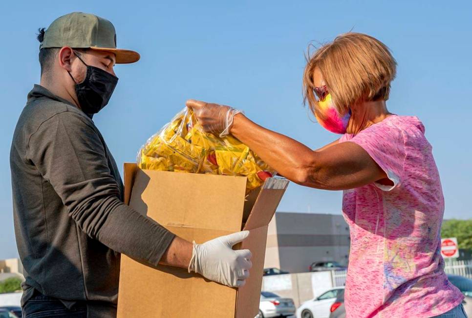 Miguel Landabazo, left, and Julie Sues-Delaney, volunteers with Three Square Food Bank, pack a ...