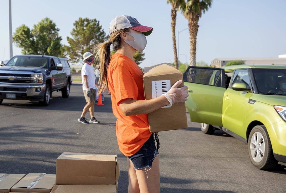 Three Square Food Bank volunteer Dinis Adams of Las Vegas distributes meals at Cannon Junior Hi ...