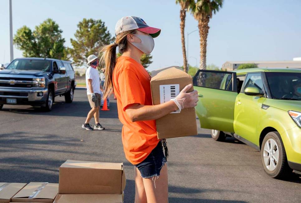 Three Square Food Bank volunteer Dinis Adams of Las Vegas distributes meals at Cannon Junior Hi ...