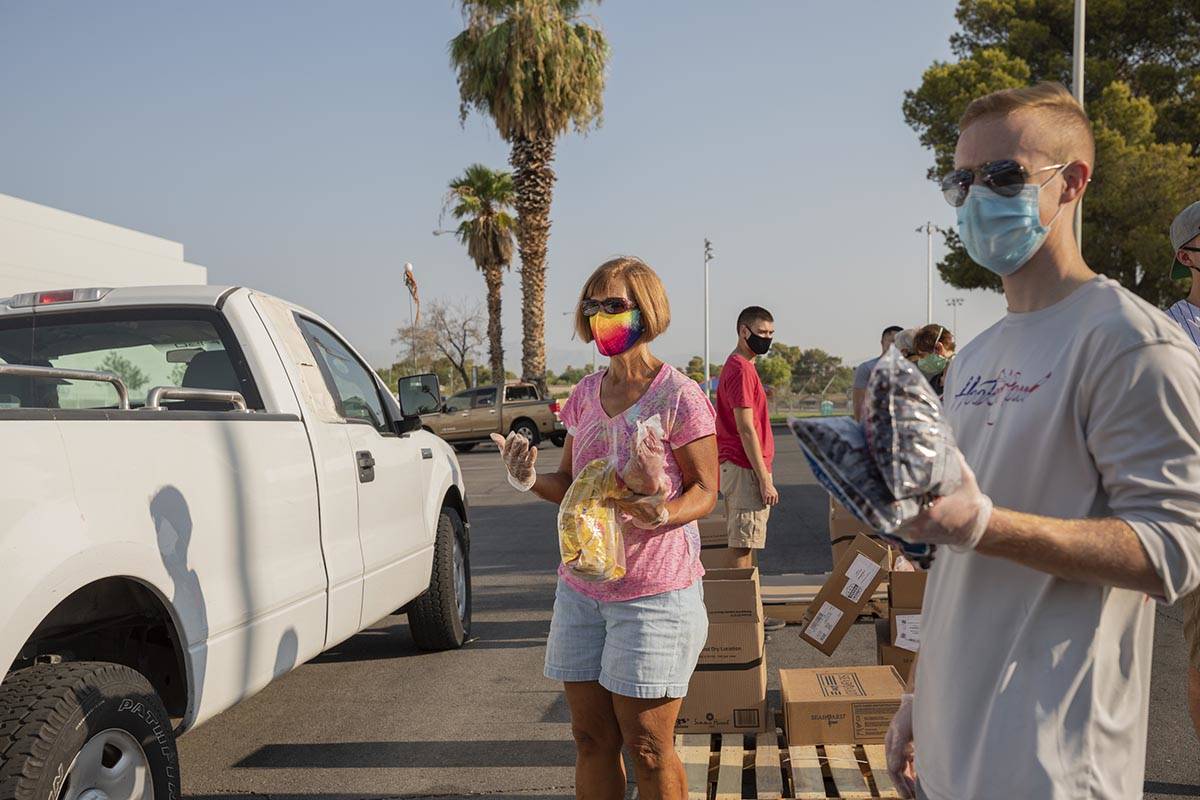 Three Square Food Bank volunteers Julie Sues-Delaney, left, and Chase Seybold usher a car forwa ...