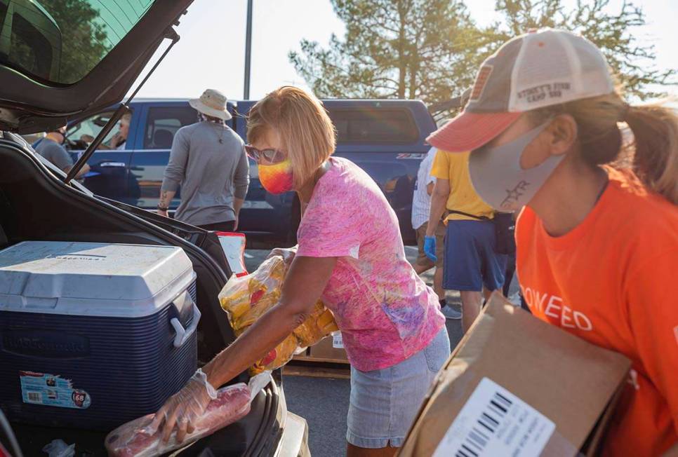 Three Square Food Bank volunteers Julie Sues-Delaney, left, and Dinis Adams load a vehicle goin ...