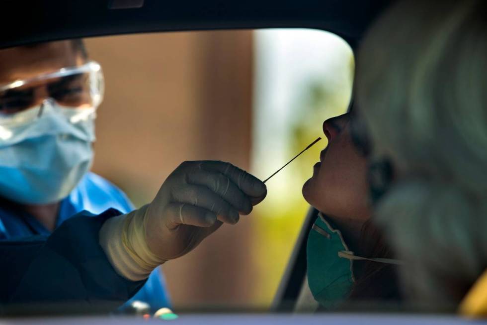 Practice Manager Jose Tirana conducts a COVID-19 test on a patient in the parking lot at Sahara ...