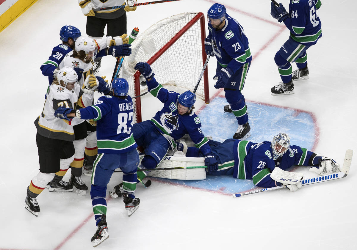 Vancouver Canucks' Troy Stecher (51) falls on goalie Jacob Markstrom (25) as there is a scrambl ...