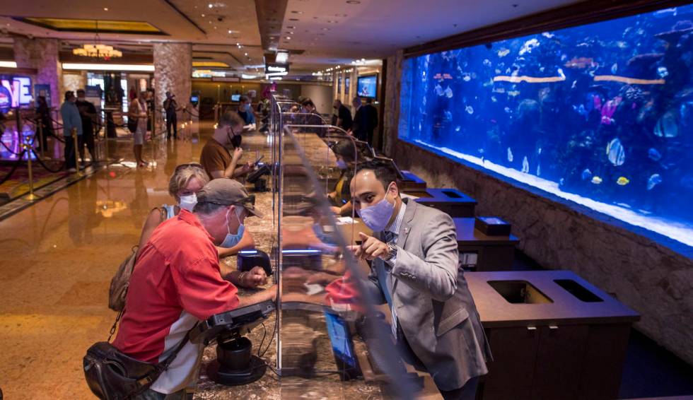 Front desk clerk Charlie Tran, right, helps to check in guests Mike and Debra Kennedy in from O ...