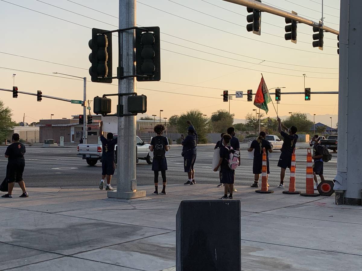 Several of the older teens with Cheyenne Little League football team stood along the sidewalk c ...