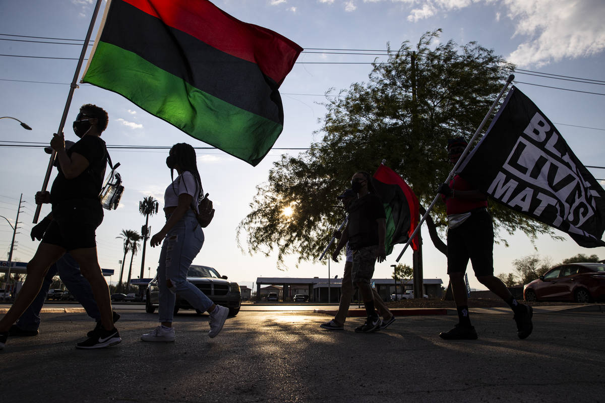 Hilary Thomas, of Henderson, left, walks with a flag while arriving at a rally against police b ...