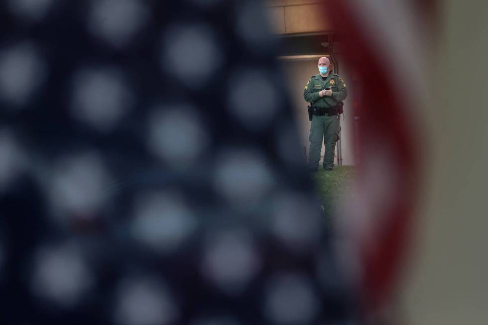 A Las Vegas police officer monitors a No Mask Nevada PAC rally from across the street at Sunset ...