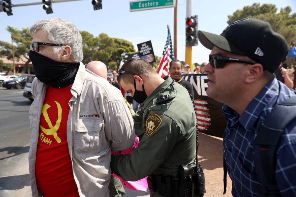 A counterprotester is detained by Las Vegas police at a No Mask Nevada PAC rally at Sunset Park ...