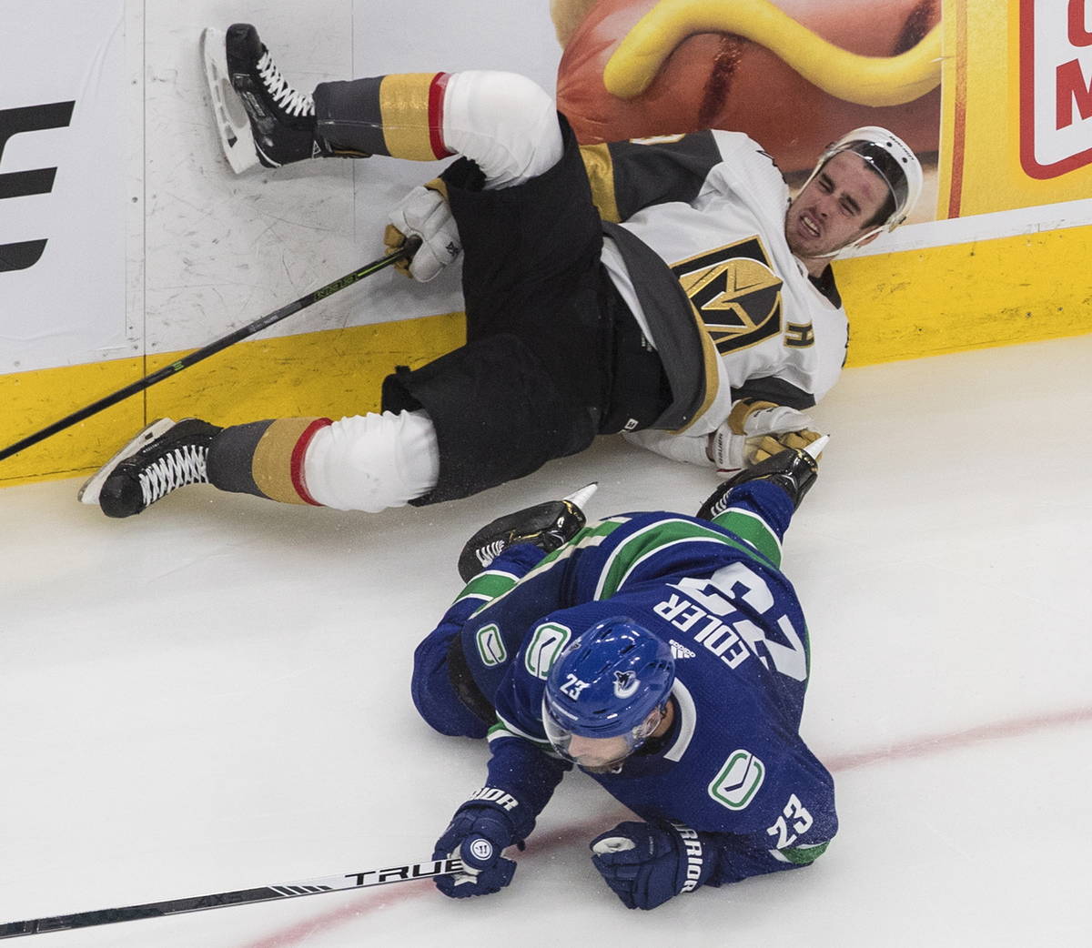 Vegas Golden Knights' Reilly Smith, top, is checked by Vancouver Canucks' Alexander Edler (23) ...