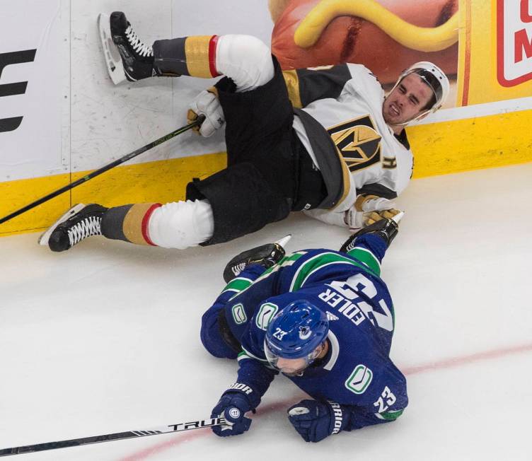 Vegas Golden Knights' Reilly Smith, top, is checked by Vancouver Canucks' Alexander Edler (23) ...