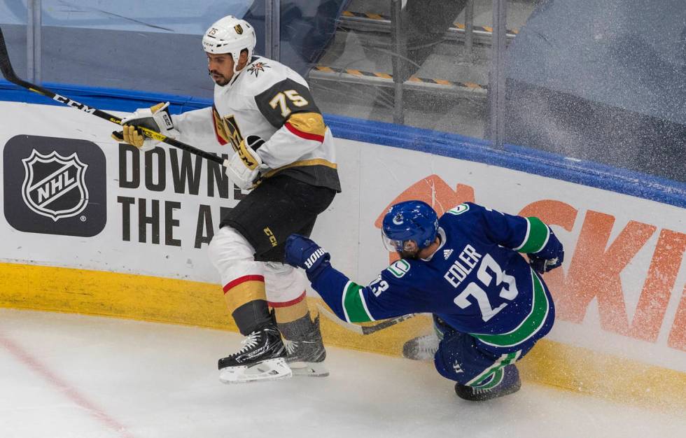 Vegas Golden Knights' Ryan Reaves (75) checks Vancouver Canucks' Alexander Edler (23) during th ...