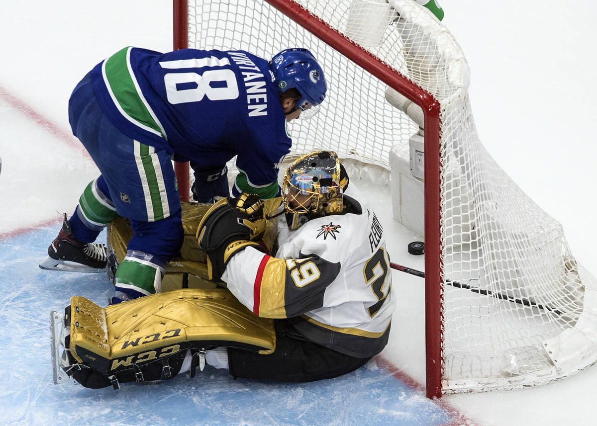 Vancouver Canucks' Jake Virtanen (18) falls on Vegas Golden Knights goalie Marc-Andre Fleury (2 ...