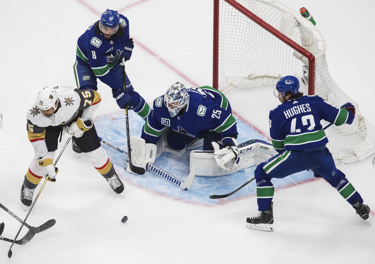 Vegas Golden Knights' Ryan Reaves (75) and Vancouver Canucks' Quinn Hughes (43) look for the re ...