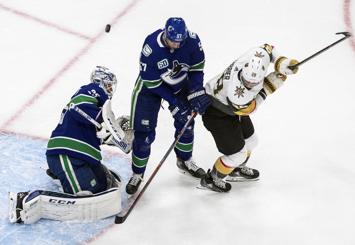 Vegas Golden Knights' William Carrier (28) and Vancouver Canucks' Tyler Myers (57) battle in fr ...