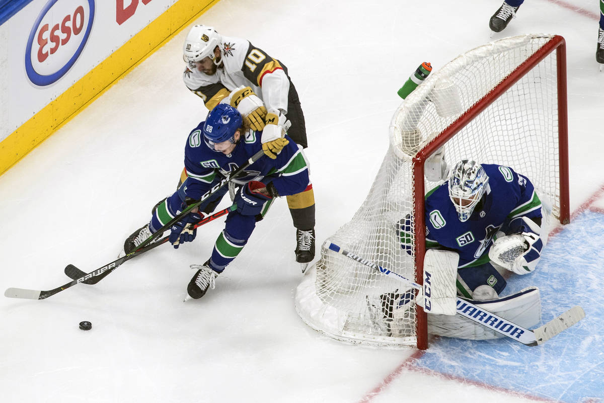 Vegas Golden Knights' Nicolas Roy (10) and Vancouver Canucks' Adam Gaudette (88) battle for the ...