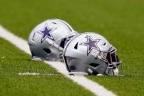 Dallas Cowboys helmets sit on the field during an NFL training camp football practice in Frisco ...