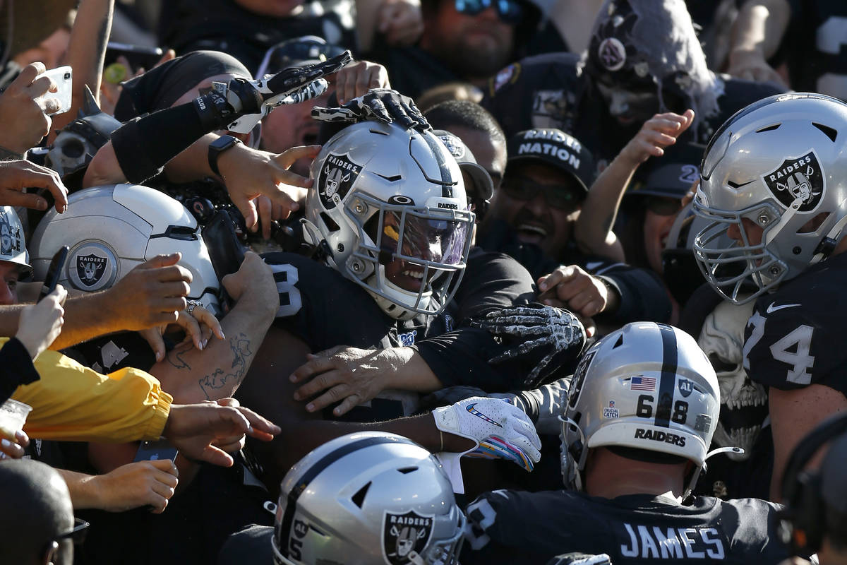 Oakland Raiders running back Josh Jacobs, center, celebrates with teammates and fans after scor ...