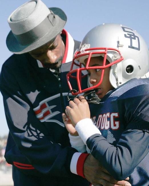 FILE - In this Feb. 5, 2005 file photo, Rap artist and actor Snoop Dogg, left, talks to his son ...