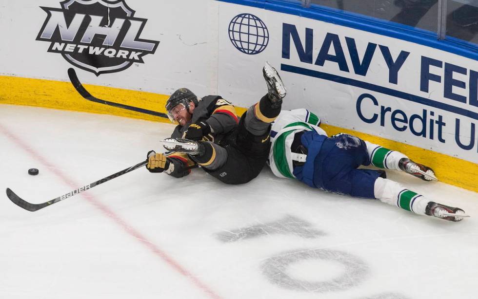 Vancouver Canucks' Troy Stecher, right, battles for the puck with Vegas Golden Knights' Nick Co ...