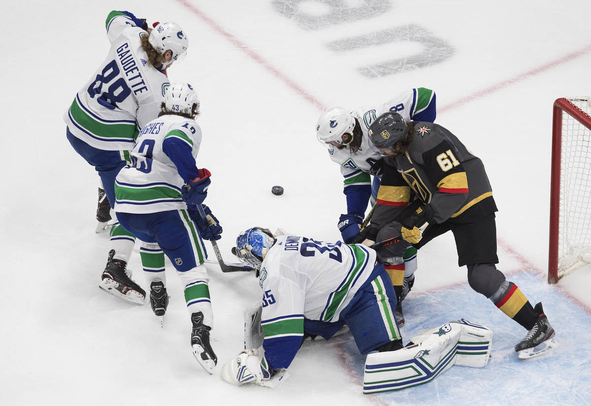 Vancouver Canucks goalie Thatcher Demko (35) makes a save as players scramble for the puck duri ...