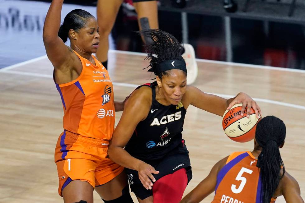 Las Vegas Aces center A'ja Wilson (22) drives between Phoenix Mercury center Kia Vaughn (1) and ...