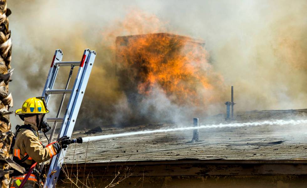 Fire burns through the roof as Las Vegas firefighters battle a house fire on 5400 block of West ...