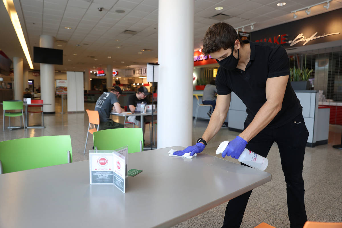 Student worker Christian Quintana cleans a table in the Student Union's food court at UNLV in L ...