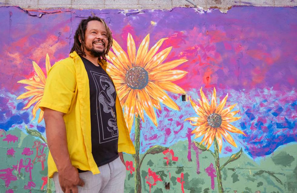 Multidisciplinary artist and community activist Brent Holmes is photographed by a mural he is w ...