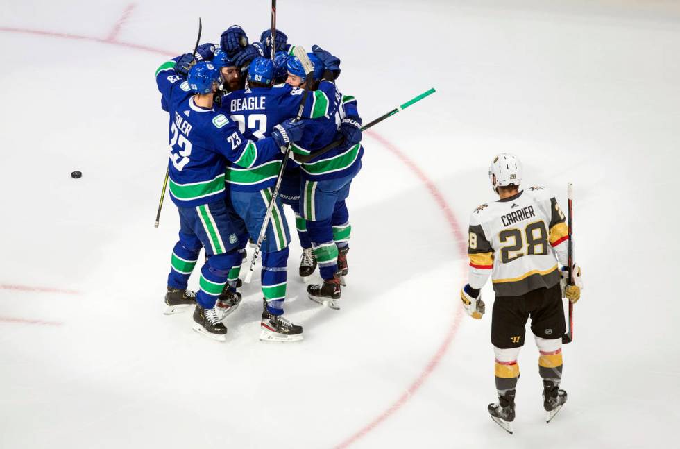 Vancouver Canucks players celebrate a goal as Vegas Golden Knights William Carrier (28) looks o ...