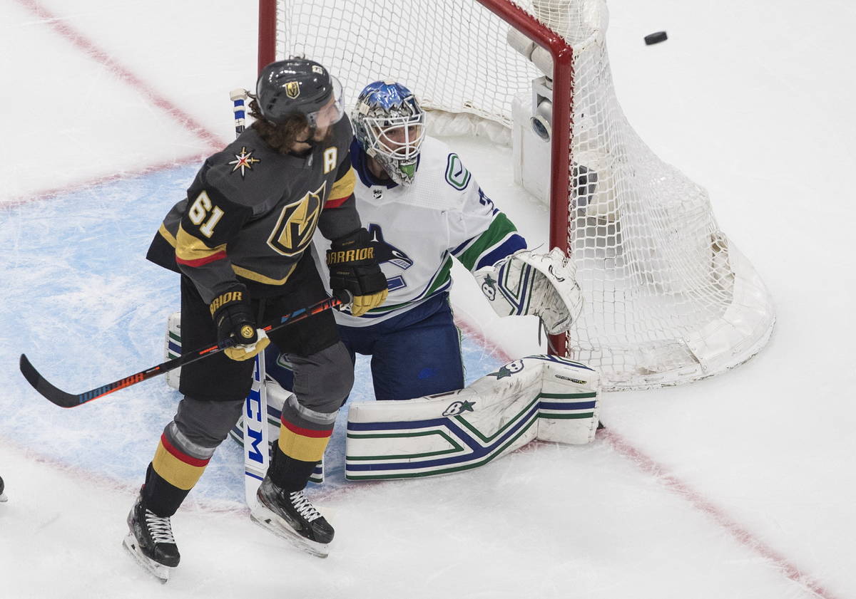 Vancouver Canucks goalie Thatcher Demko (35) and Vegas Golden Knights' Mark Stone (61) look for ...