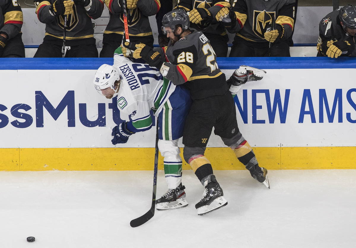 Vancouver Canucks' Antoine Roussel (26) is checked by Vegas Golden Knights' William Carrier (28 ...