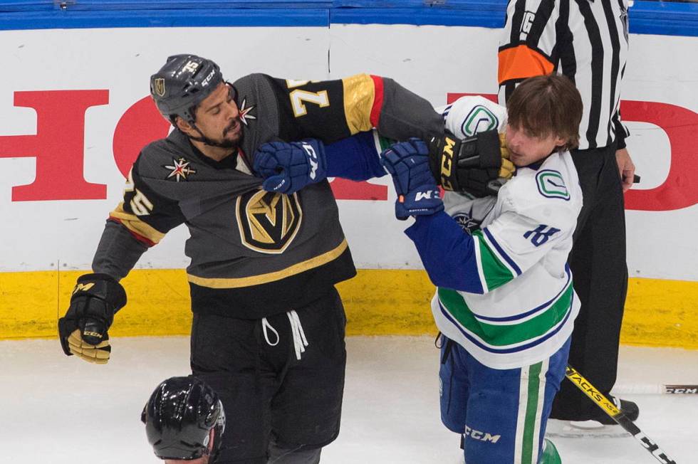 Vancouver Canucks' Jake Virtanen (18) and Vegas Golden Knights' Ryan Reaves (75) rough it up du ...