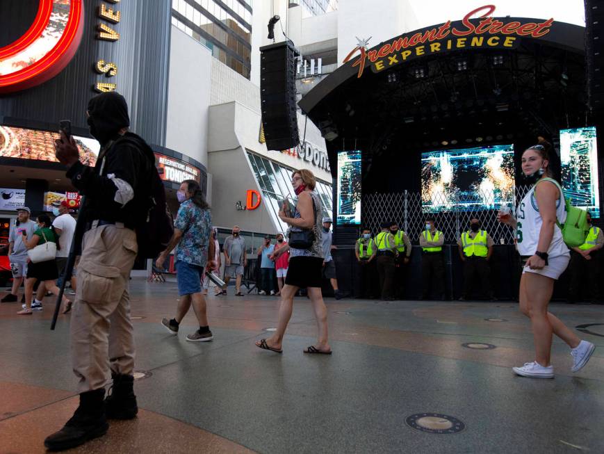 Security guards stand watch as Fremont Street Experience attendees pass the "Justice For B ...