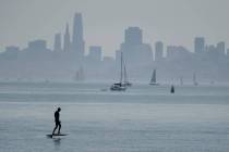A man rides a powered surfboard on the bay with the San Francisco skyline in the background Sat ...