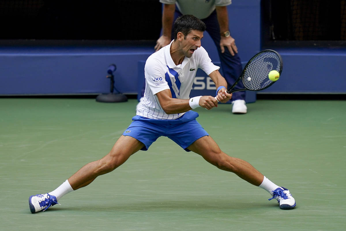 Novak Djokovic, of Serbia, returns a shot to Pablo Carreno Busta, of Spain, during the fourth r ...