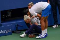Novak Djokovic, of Serbia, checks a linesman after hitting her with a ball in reaction to losin ...