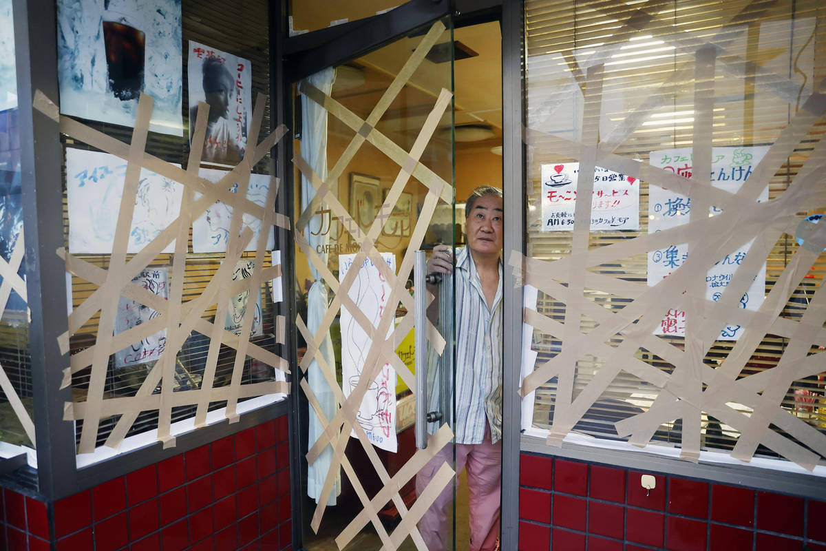 An owner of a coffee shop looks outside as his shop windows are taped in the preparation for ap ...