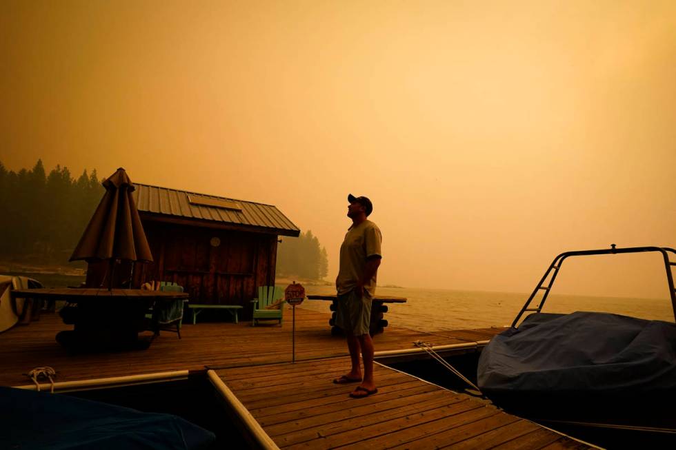 A business owner, who declined to give his name, looks up at the smoke-covered sky from the Cre ...