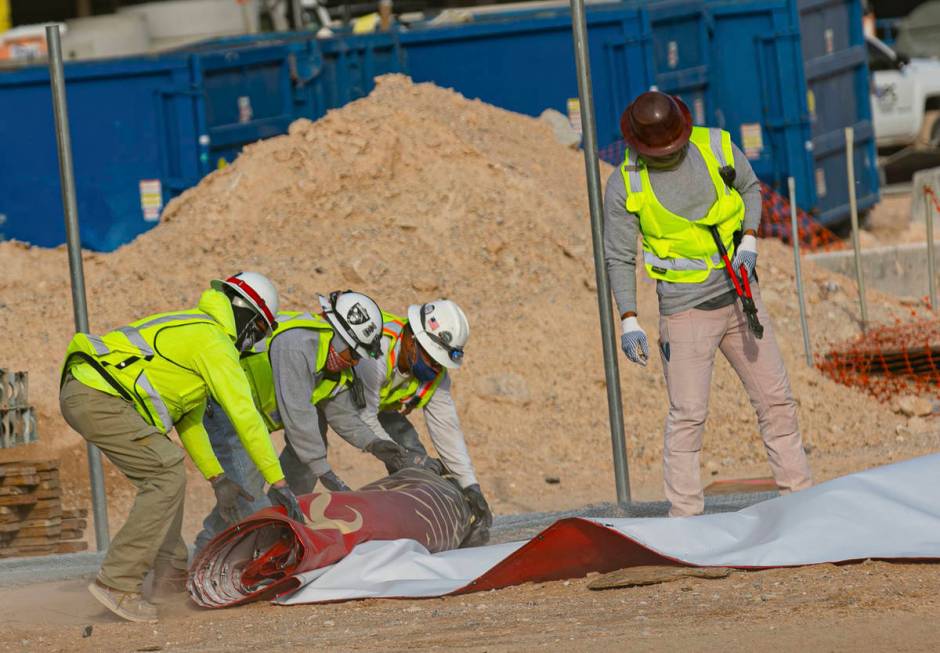 Construction workers try to recover the Resorts World construction site sign after heavy wind k ...