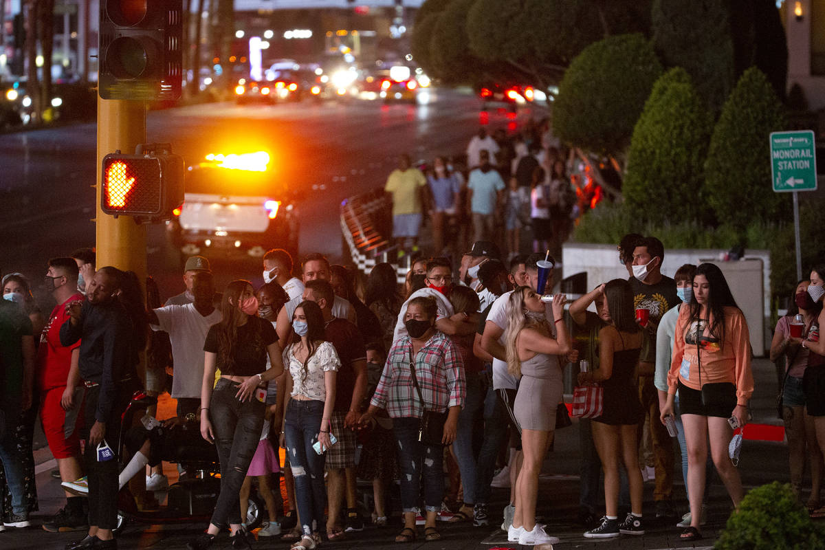 Visitors wait to cross the street outside Caesars Palace on the Strip during Labor Day weekend ...